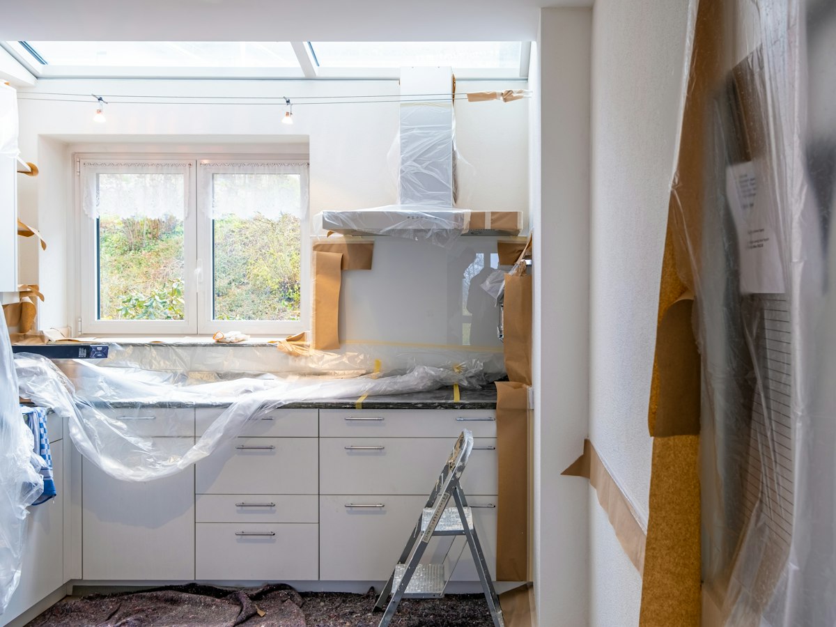Kitchen near the end of a renovation, counters and hood still wrapped in plastic, ready for the final clean