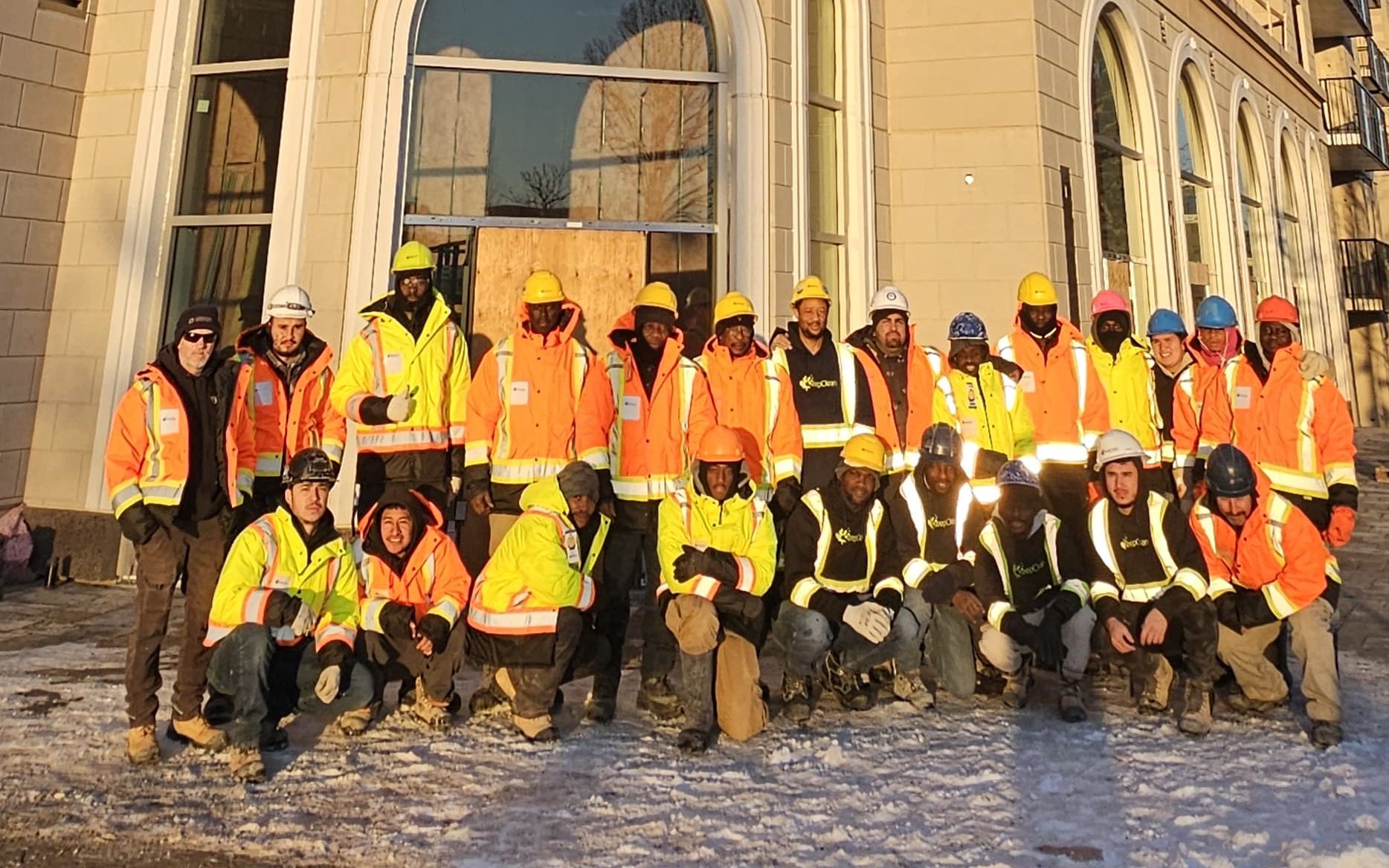 The Keep Clean crew in hi-vis jackets and hard hats, gathered in front of a finished building